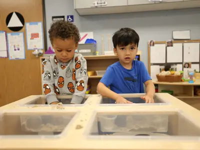 Two young boys engaged in sandbox activity in classroom