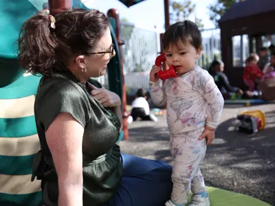 Care provider engaging with toddler talking on plastic phone