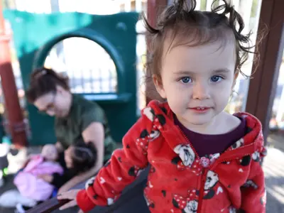 Young child smiling standing in outdoor play area