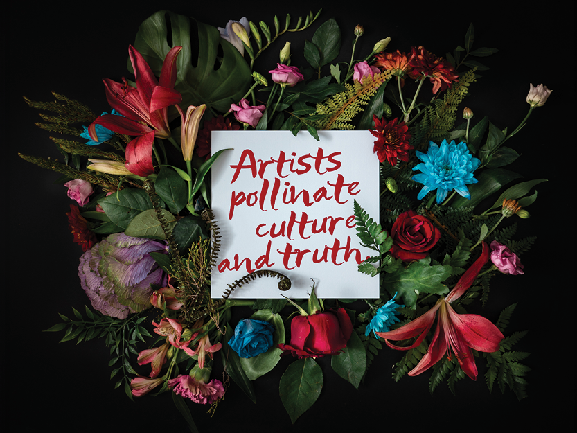 flower wreath with a white card in the middle, the card features a quote written in a bold, red script: "Artists pollinate culture and truth."