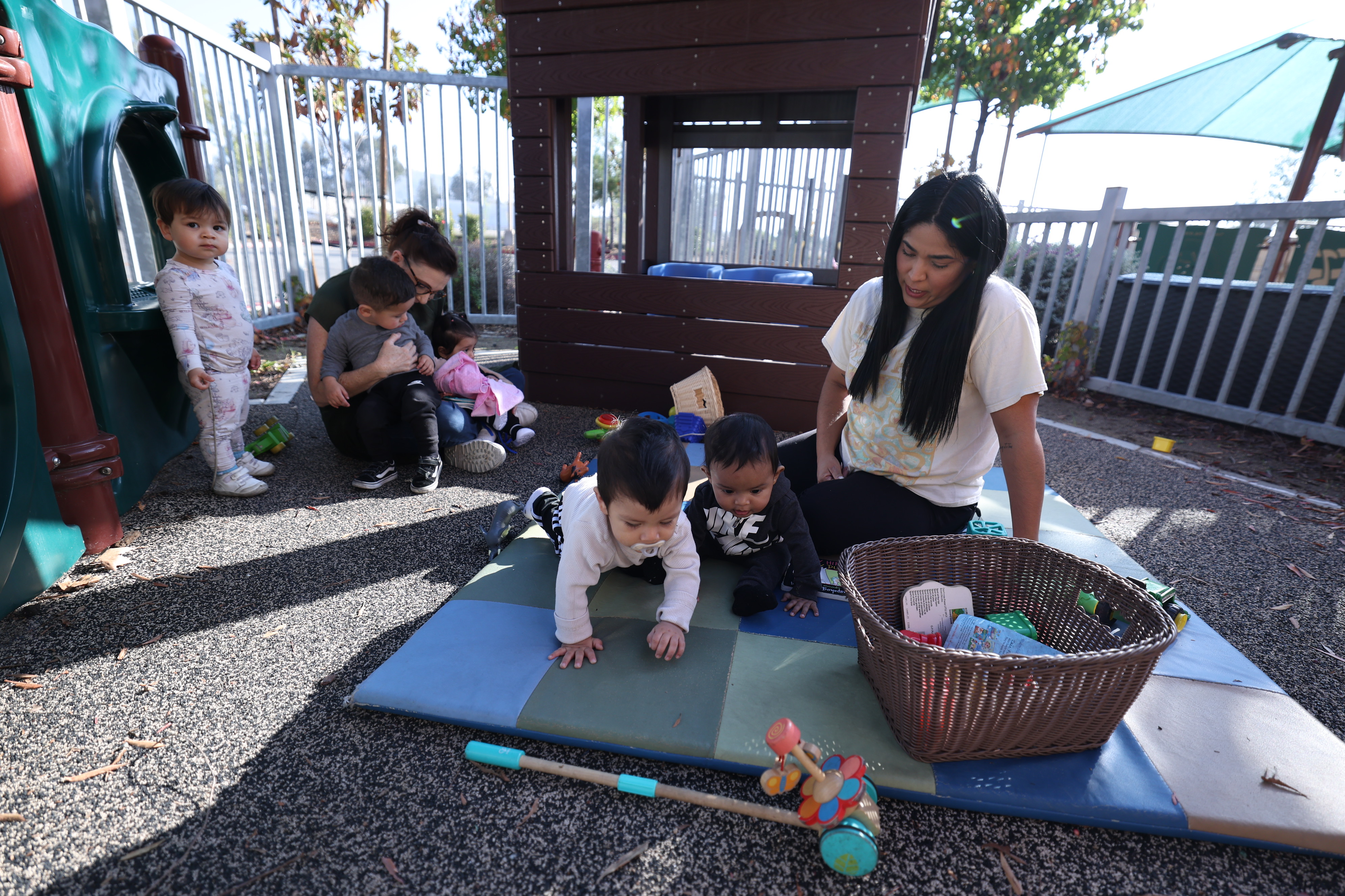 Outdoor child care setting with care providers attending to multiple children