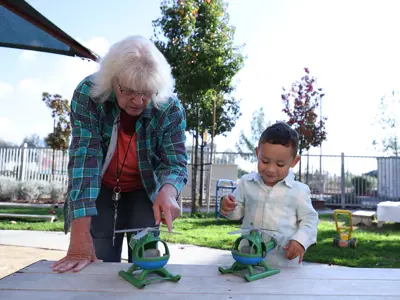 Child Care Provider and young boy examining matching helicopter toys